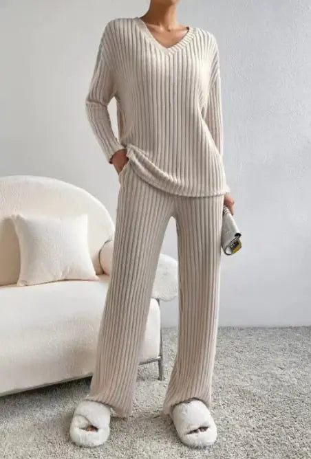 Person wearing a beige ribbed knit outfit with matching slippers in a cozy room.